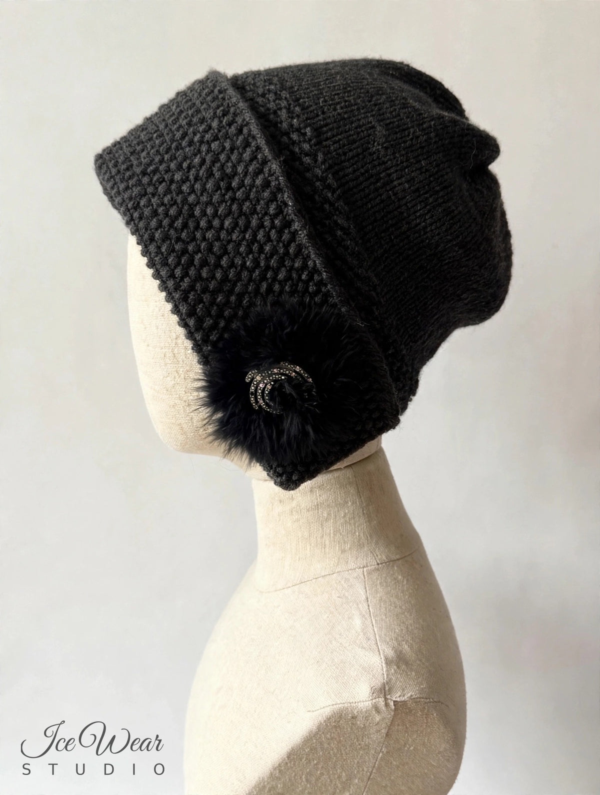 Black hand-knitted earflap cloche, side view on linen mannequin