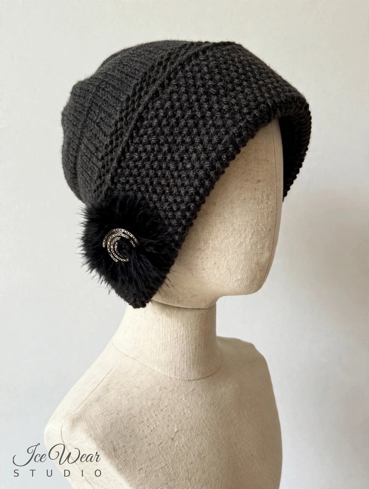 Black hand-knitted earflap cloche, three-quarter view on linen mannequin
